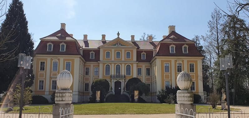 Ein prächtiges gelbes Herrenhaus mit roten Dächern, flankiert von Grünanlagen